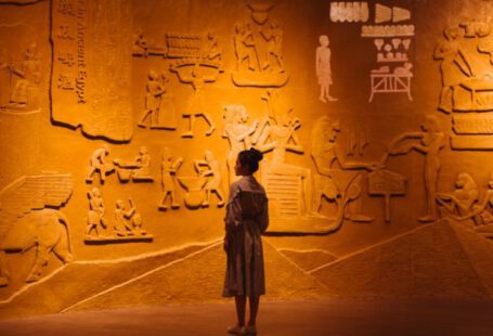 Wi-Fi Encryption - Back view of anonymous female traveler standing near ancient wall with Egyptian engraving