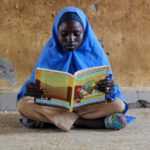 Customizable Learning - Young Girl Sitting and Reading a Textbook