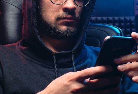 Phishing - A Man in Black Hoodie Sweater Using His Mobile Phone