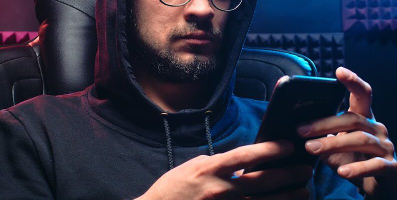 Phishing - A Man in Black Hoodie Sweater Using His Mobile Phone